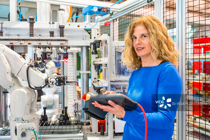 工程师在工厂控制机器人，看向镜头图片素材