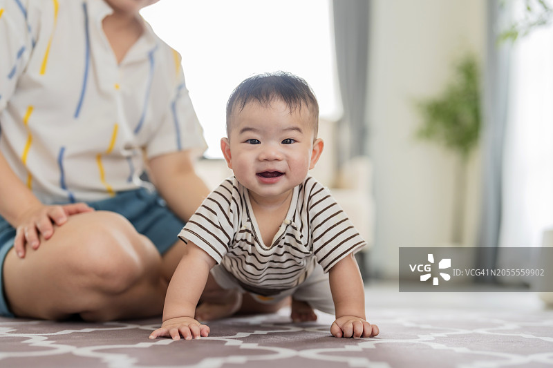 亚洲家庭温馨日常：宝宝学爬，妈妈在一旁鼓励支持图片素材