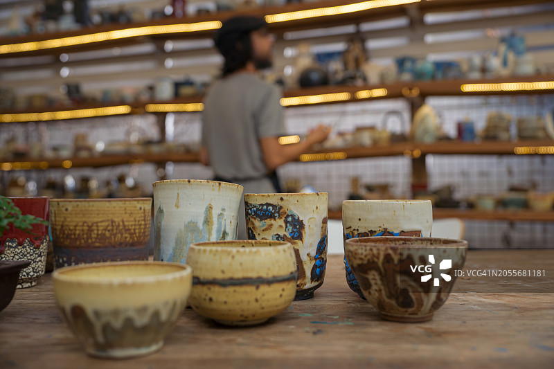 陶艺工作室中的各种手工陶瓷杯，陶工在检查货架库存图片素材