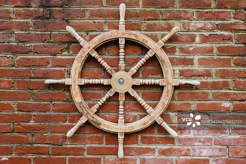 固定在砖墙上的装饰船舵图片素材