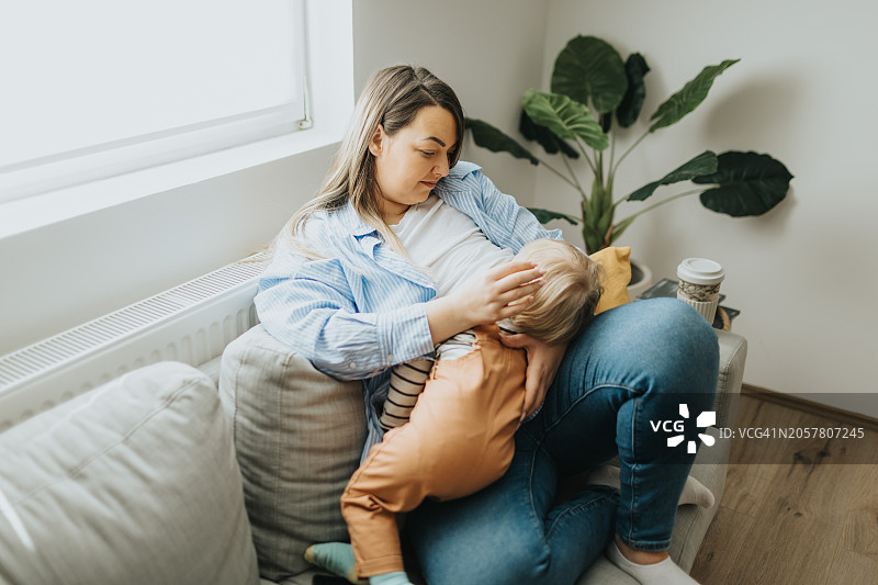 年轻母亲在家给宝宝喂母乳图片素材