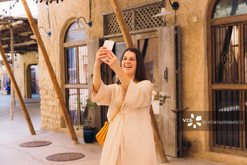 在迪拜老城区拍照的微笑女游客图片素材