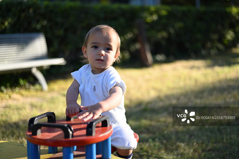 坐在操场跷跷板上的可爱女孩肖像图片素材