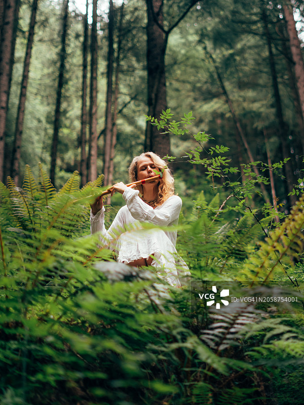 女子在森林中吹奏长笛的肖像图片素材