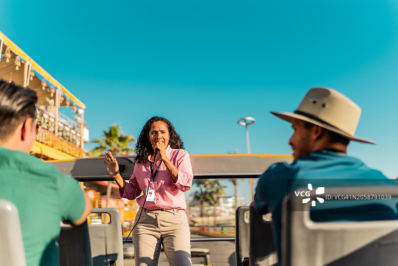 中年女导游在旅游巴士上与游客交谈图片素材