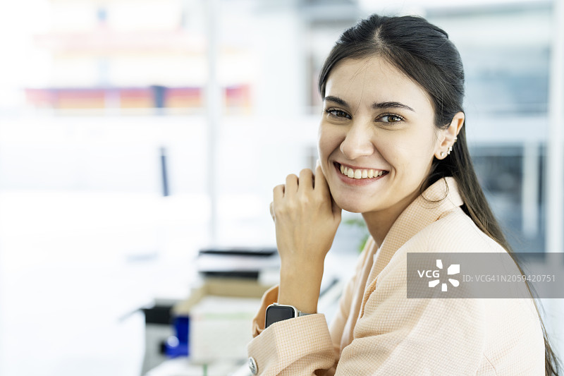 看着镜头，交叉双臂的年轻微笑女人肖像图片素材