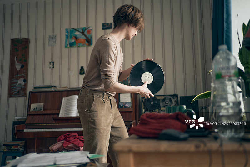 戴眼镜的年轻男子在客厅里播放黑胶唱片图片素材