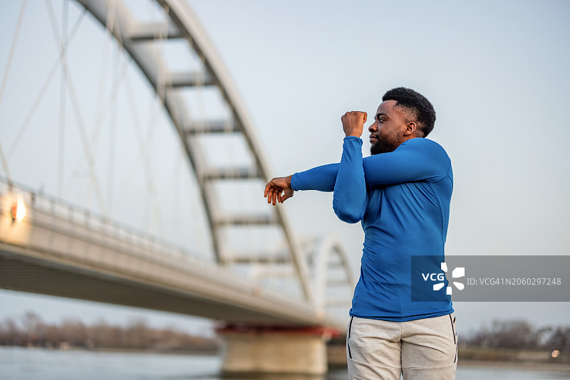 户外运动：年轻男子伸展手臂图片素材