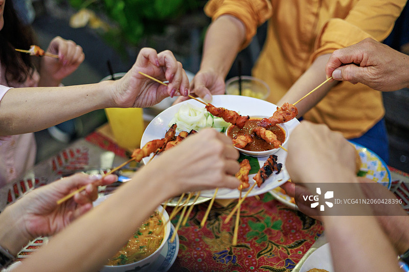 朋友们一起享用美味烤鸡肉沙爹街头小吃的高角度视图图片素材