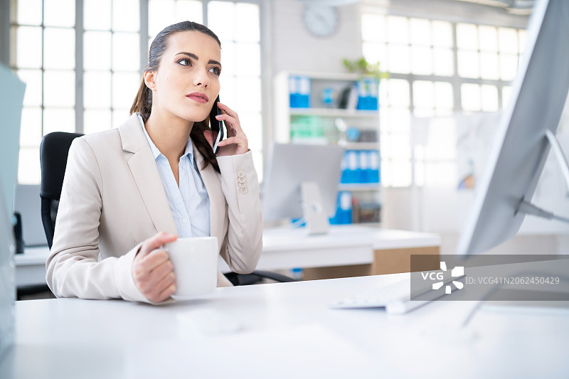 在办公室用智能手机交谈的商务女性图片素材