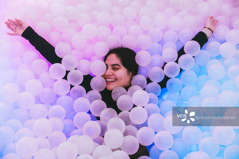 一个沉浸在凉爽球池中的拉丁女人做梦的肖像图片素材