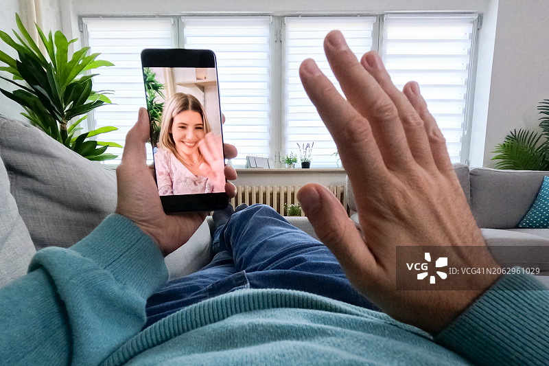 年轻男人在家躺在沙发上与女性朋友进行视频通话图片素材