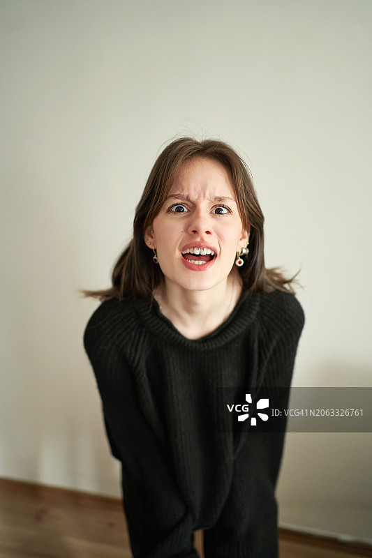 愤怒的年轻棕发女子肖像，休闲装扮，站立着，喊叫着，尖叫着，看着镜头图片素材