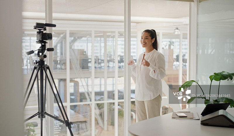 商务女性在办公室用相机录制演示文稿，用于在线指导、直播和大师班网络研讨会。内容创作者、员工和数字设备，通过视频博客服务网站图片素材