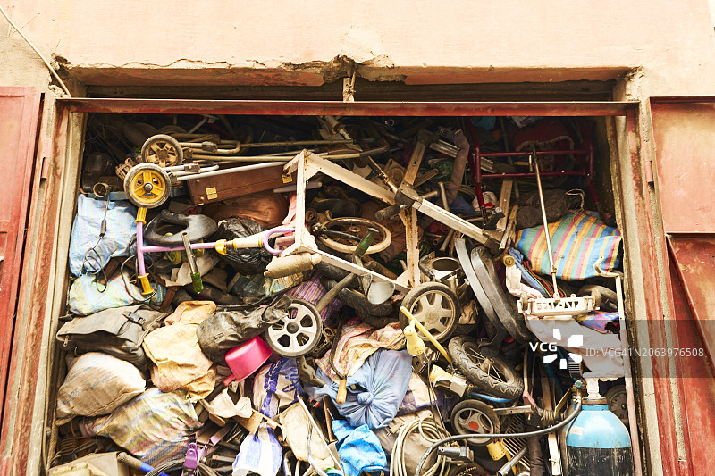 一个旧仓库的敞开的门，里面堆满了杂乱无章的旧东西。图片素材