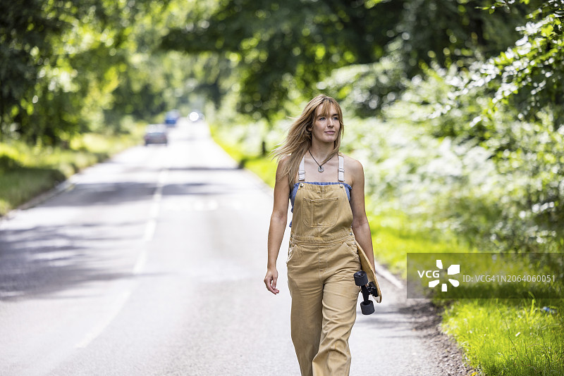 年轻女人在森林里玩滑板图片素材