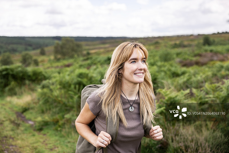 快乐的年轻女子在森林里背着背包徒步旅行图片素材