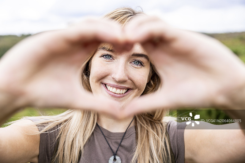 快乐的年轻女子做出心形手势图片素材