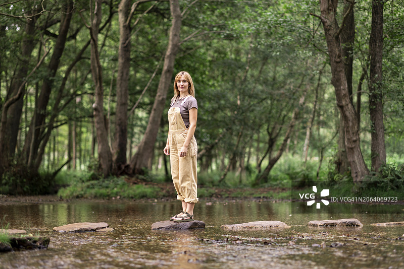 年轻女子站在树前的岩石上图片素材