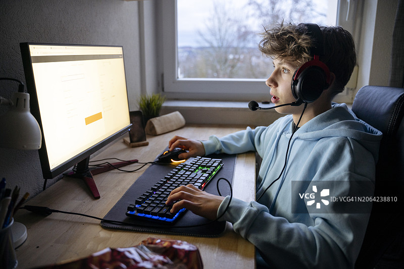 戴着耳机在电脑前玩游戏的男孩图片素材