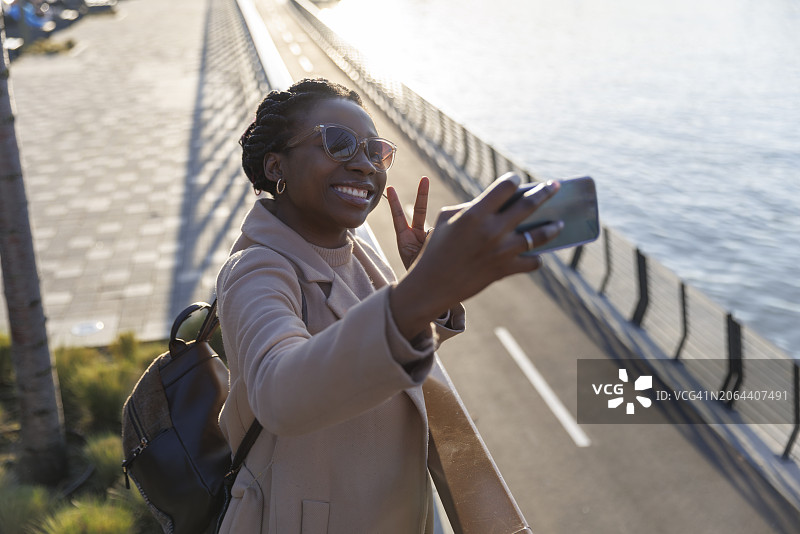 微笑女人在河边比V手势自拍图片素材