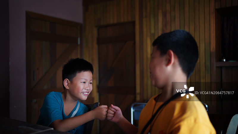 两个快乐的亚洲男孩在餐厅里碰拳图片素材