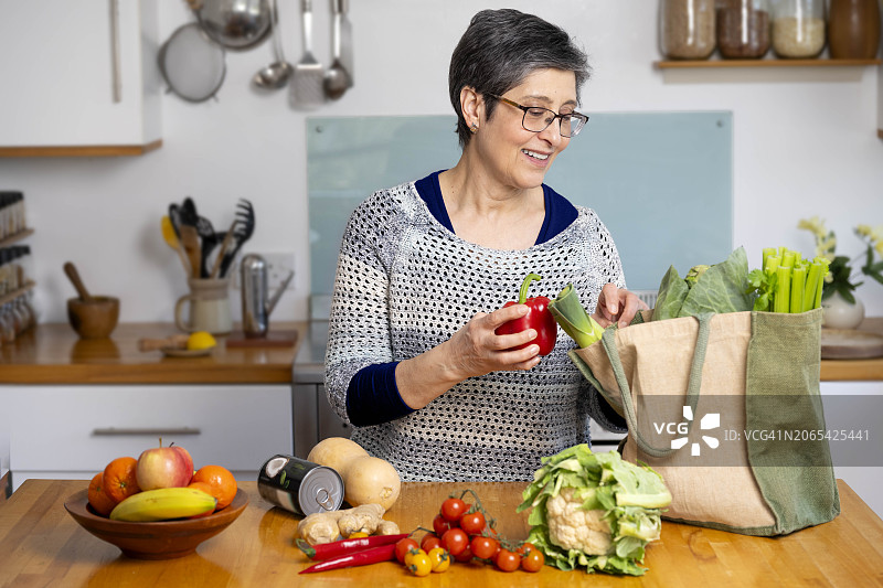 女人在家庭厨房里取出食品杂货图片素材