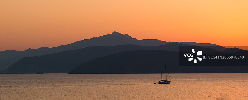 橙色天空下航行在海上的帆船剪影图片素材
