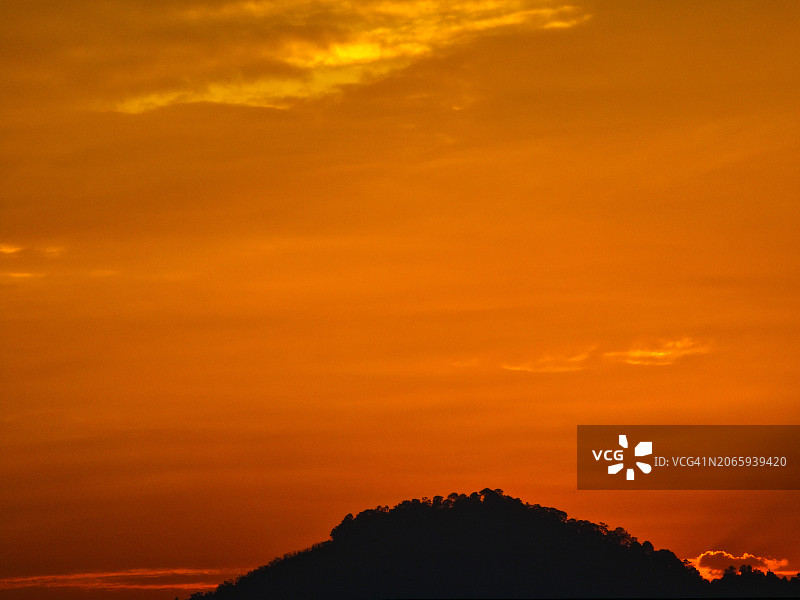 马来西亚吉打州居林的橙色天空下的山脉轮廓图片素材