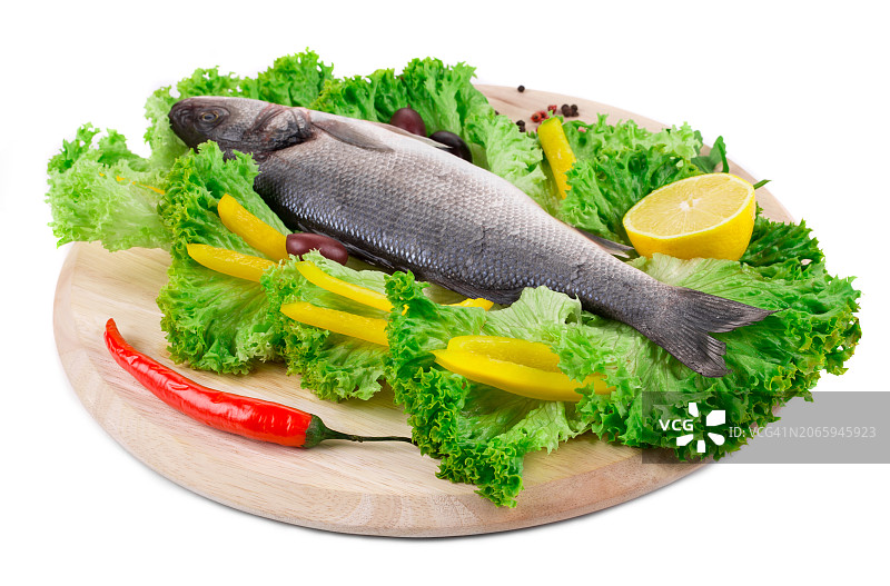 白背景下砧板上的鲈鱼和蔬菜特写图片素材