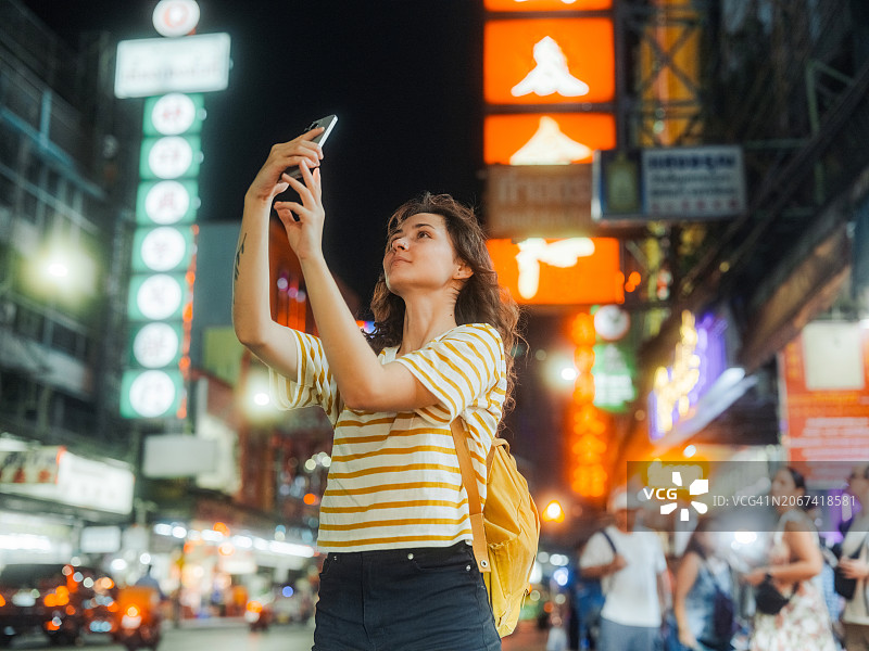 女人用智能手机在曼谷唐人街游览拍摄图片素材