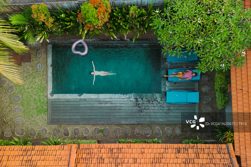 在别墅泳池边休息的男人和女人的航拍图片素材