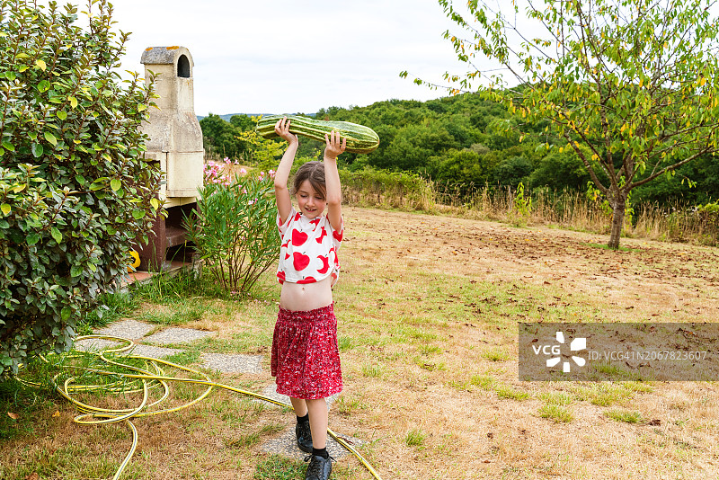 在花园里玩耍和收集蔬菜的小女孩全身像图片素材
