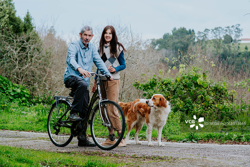 带着自行车和狗在公园里的快乐中年夫妇图片素材