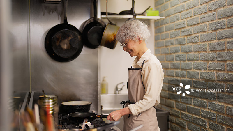 在餐厅咖啡厅的商业厨房里做饭的年长女性图片素材