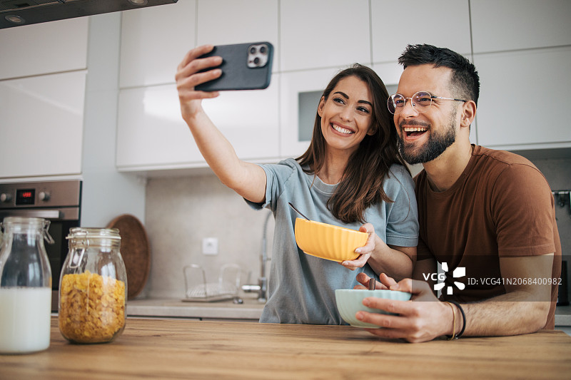 情侣一起制作早餐并使用智能手机图片素材