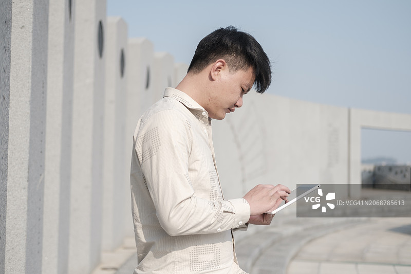 亚洲男人在户外使用平板电脑图片素材