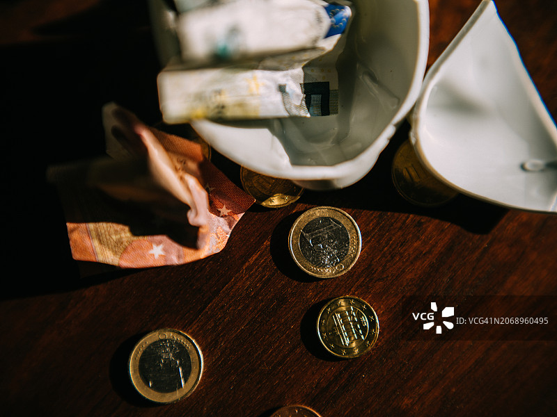 装满欧元硬币的破损小猪储蓄罐俯视图图片素材