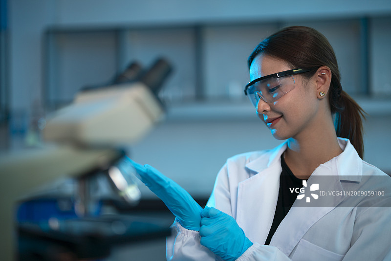 戴着防护手套在实验室工作的年轻女科学家图片素材