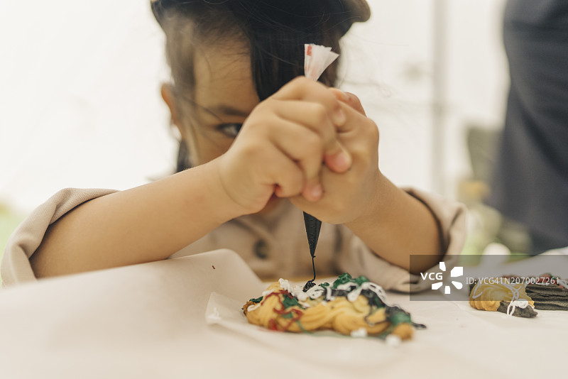 年轻女孩专注地在烹饪烘焙工坊的桌子上制作饼干图片素材