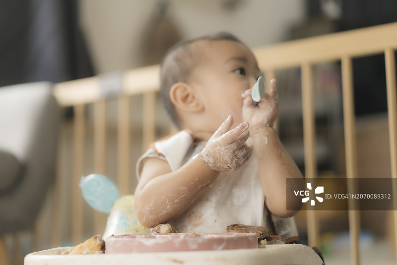饥饿的亚洲宝宝（10个月大）在饭前哭闹的表情特写：情绪化的用餐挣扎图片素材