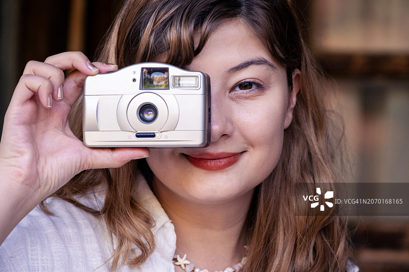 年轻女子用35毫米胶片相机拍照图片素材