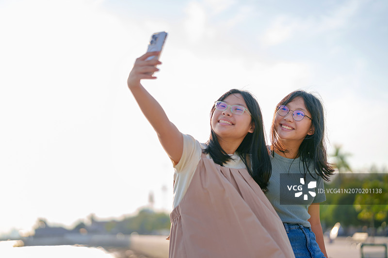 快乐的年轻兄妹在旅行时用智能手机自拍，用科技捕捉和保存旅行记忆图片素材