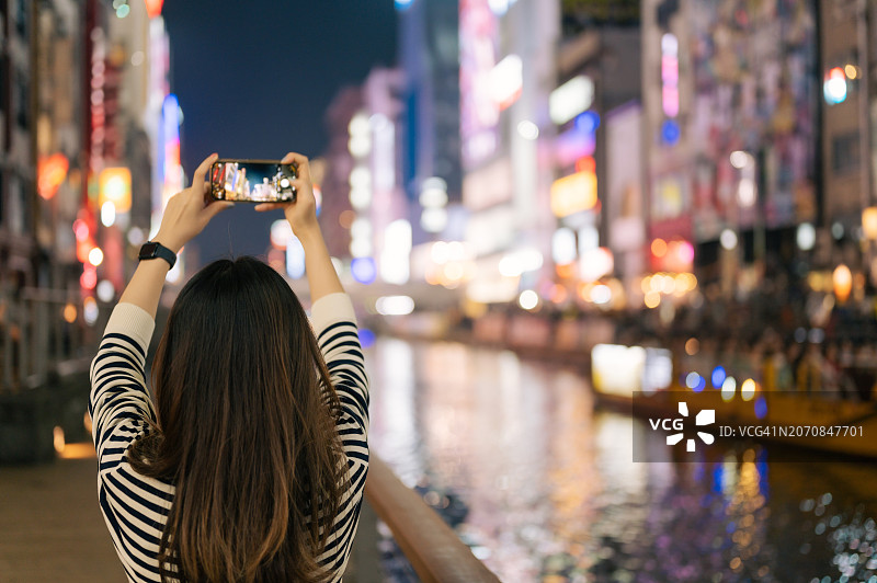 亚洲Gen Z网红用他的微单相机录制延时摄影，拍摄大阪道顿堀的城市风光图片素材