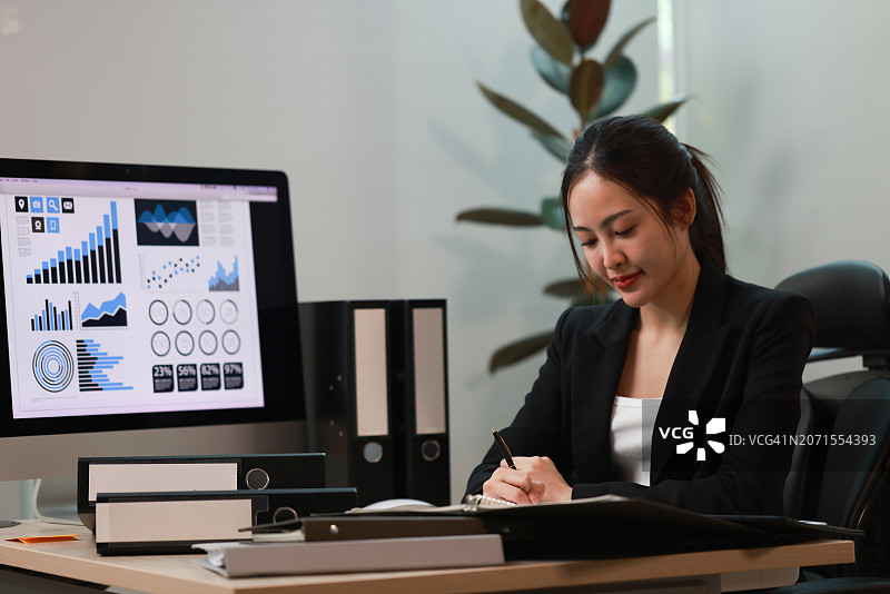 专心致志的亚洲女商人分析电脑上的在线销售统计数据，审查市场调研，在联合办公空间处理文件图片素材