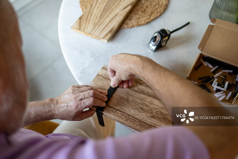 年长的男人在家里的厨房用螺丝刀组装家具图片素材