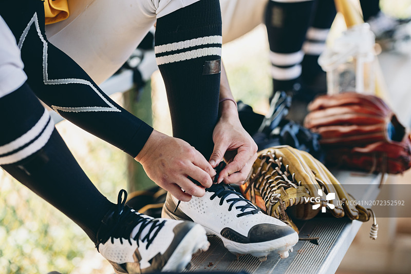 棒球运动员专注地系鞋带，准备随时上场比赛的特写镜头图片素材