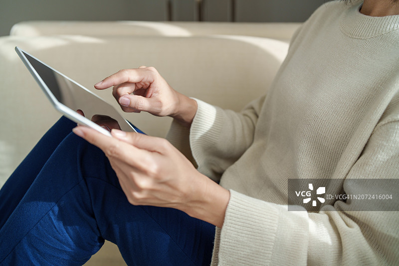 特写镜头：亚洲女性在沙发上使用平板电脑居家办公图片素材