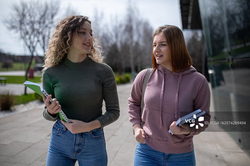 两位微笑的女大学生一起散步图片素材