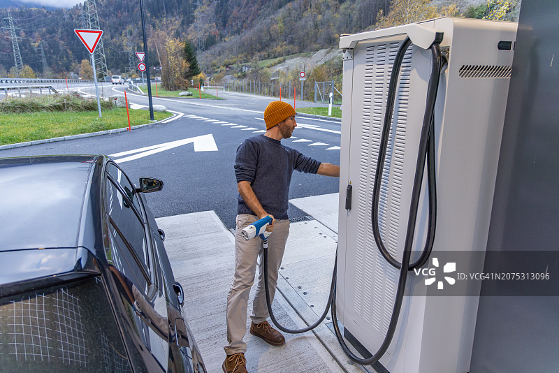 男人在公共充电站给电动汽车充电图片素材